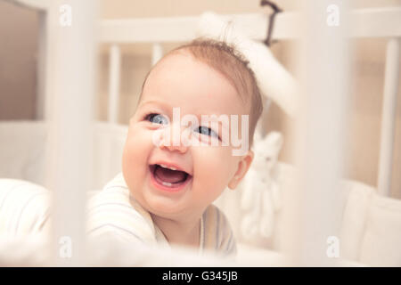 Funny laughing baby girl in cot Stock Photo