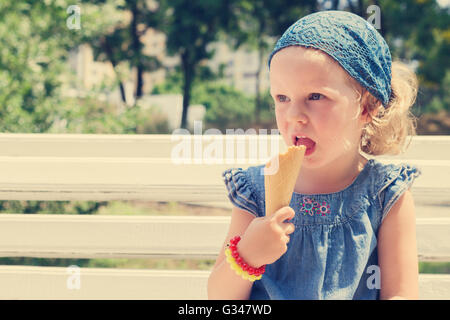 Funny little girl (3 years) eat ice cream. Selective focus. Stock Photo