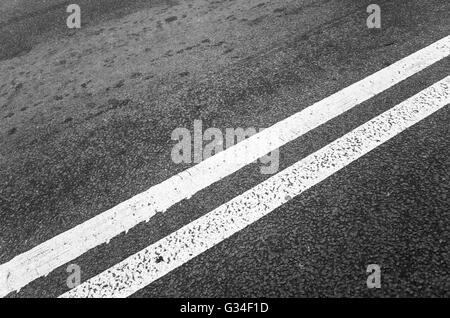 White double dividing line over black highway asphalt, closeup photo with selective focus Stock Photo