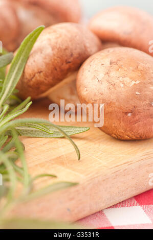 Chestnut mushrooms and rosemary on a cutting board Stock Photo
