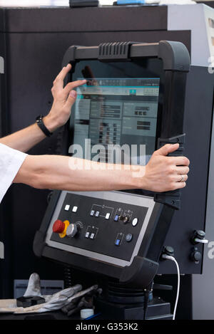 Engineer's hand on working computer panel of CNC machine Stock Photo