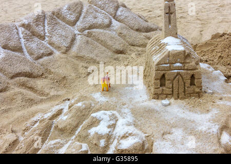 Small castle built of sand on beach is guarding of toy dog Stock Photo