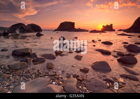 Sea stacks and natural arch along the coast near Ballintoy Harbour on the Causeway Coast of Northern Ireland at sunset. Stock Photo