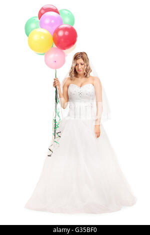Full length portrait of a sad young bride holding a bunch of balloons isolated on white background Stock Photo