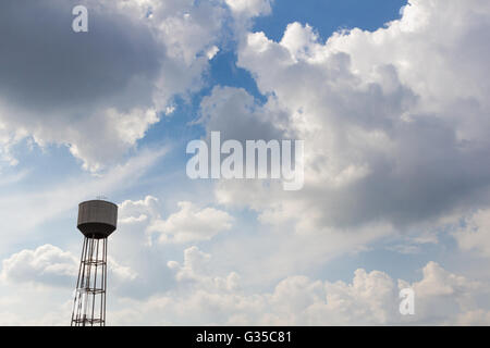 An old rusty water tower over a cloudy blue sky Stock Photo - Alamy