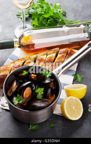 Mussels in copper pot and white wine on stone table Stock Photo