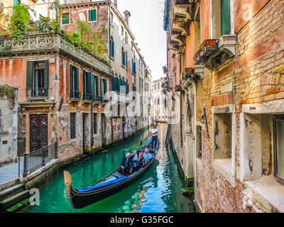 Traditional Gondolas on narrow canal between colorful historic houses in Venice, Italy Stock Photo