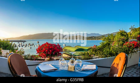 Romantic dinner place with idyllic panoramic view of mediterranean coastal landscape at sunset in golden evening light Stock Photo