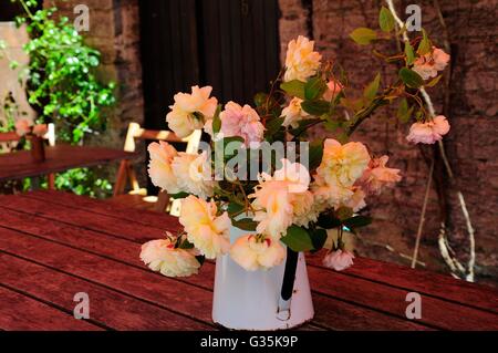 peony flowers in a vintage enamel jug on a rustic wooden table Stock Photo