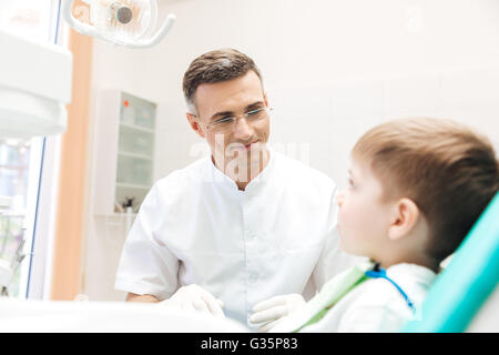 Dentist examining teeth of little boy sitting in dentists chair Stock Photo