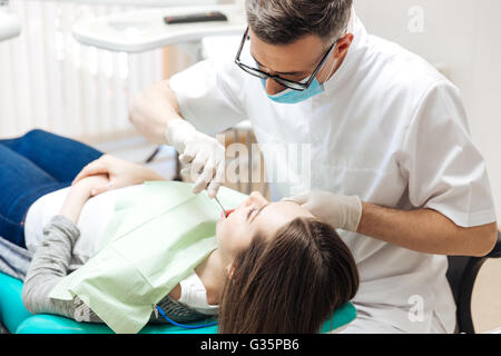 Professional dentist doing teeth checkup on female patient dental surgery in clinic Stock Photo