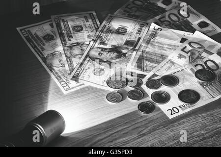 In a dark room a beam of light of the electric lantern lights money lying on the table. Stock Photo