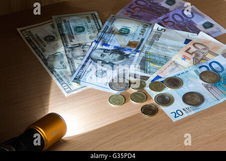 In a dark room a beam of light of the electric lantern lights money lying on the table. Stock Photo