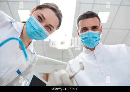 The two dentists in dental office making treatment looking at camera in clinic Stock Photo