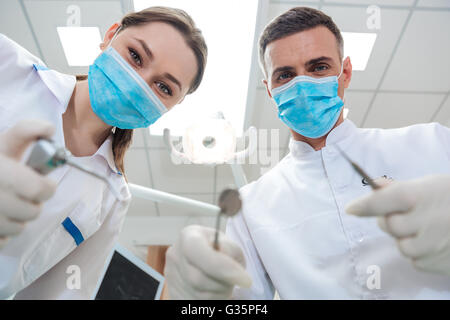 Two dentists making treatment to a patient in clinic Stock Photo