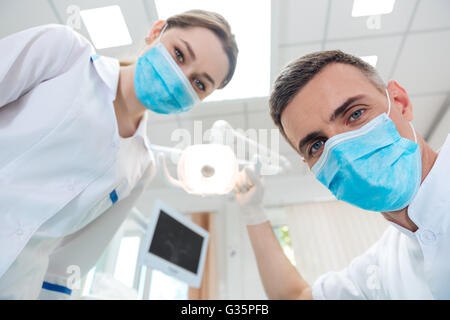 Two dentists making dental treatment to a patient in clinic Stock Photo