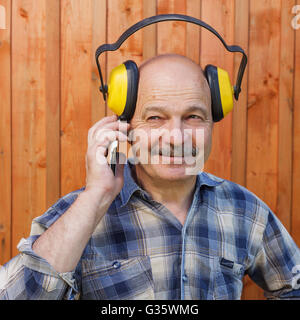 Construction worker in protective headphones during a break talking on the phone Stock Photo