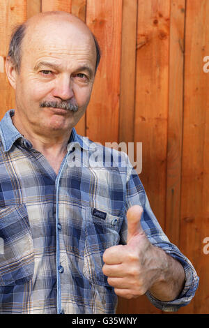 elderly man with a mustache and a bald head approves the choice. Show thumbs up. Stock Photo