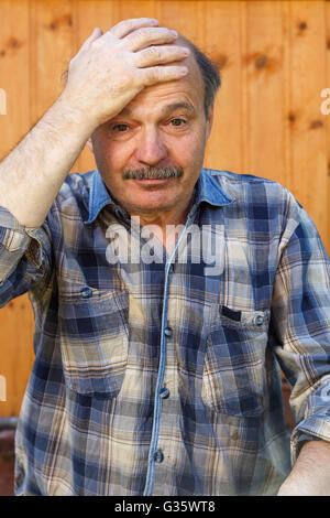 Elderly man suffering from a headache, putting his hand on his forehead Stock Photo