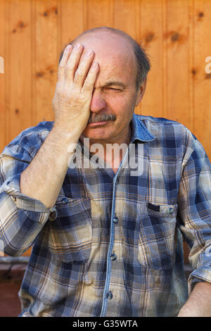 Elderly man suffering from a headache, putting his hand on his forehead Stock Photo