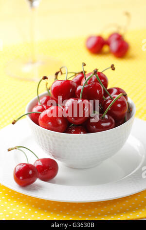 A bowl of fresh red cherries on a yellow background Stock Photo