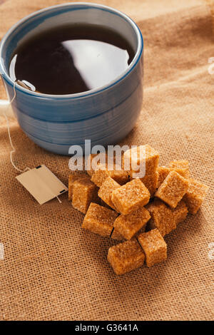 blue cup of tea and lump sugar on sacking  background Stock Photo