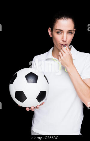 Female athlete blowing a whistle and holding a soccer ball Stock Photo