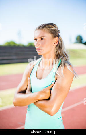 Female athlete standing with arms crossed on the running track Stock Photo