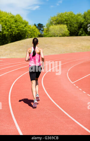 Rear view of female athlete running on the running track Stock Photo