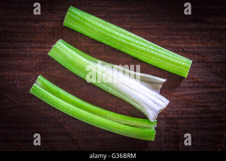 Three celery sticks on dark wooden background. Top view Stock Photo
