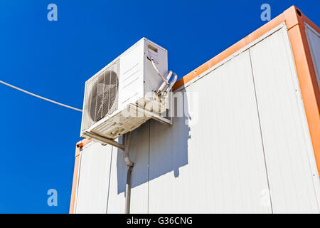 Outdoor unit, compressor, of air conditioner is placed on white container office. Stock Photo