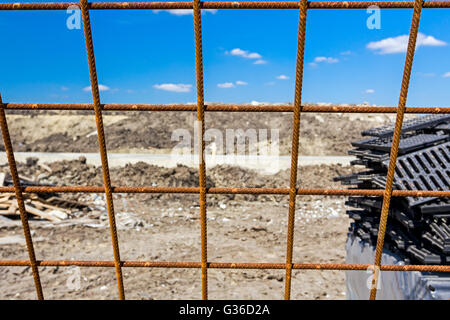 Rusty concrete reinforcement, steel bars, construction site is in background. Stock Photo