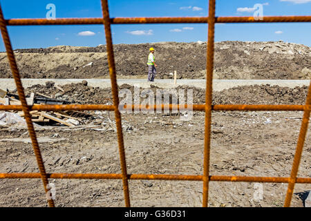 Rusty concrete reinforcement, steel bars, construction site is in background. Stock Photo