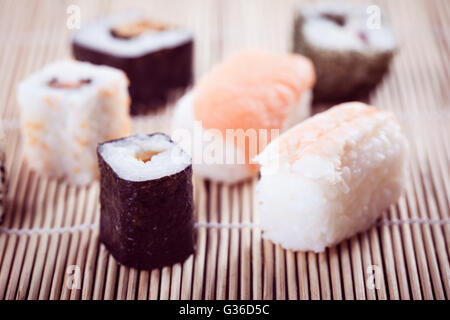 an assortment of different sushi pieces on a wooden bamboo sushi mat in a japanese restaurant Stock Photo