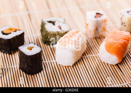 an assortment of different sushi pieces on a wooden bamboo sushi mat in a japanese restaurant Stock Photo
