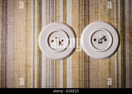 close up shot of old and obsolete light switch on a wall covered in wallpaper Stock Photo