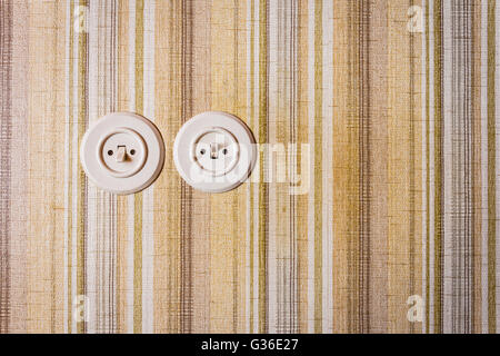 close up shot of old and obsolete light switch on a wall covered in wallpaper Stock Photo