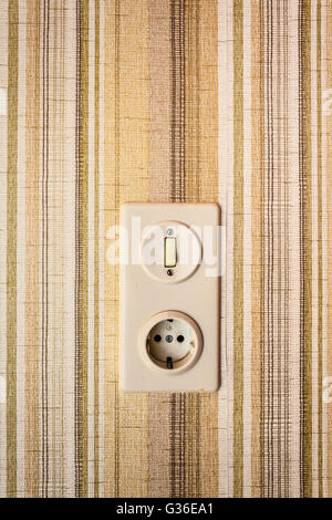 close up shot of old and obsolete light switch on a wall covered in wallpaper Stock Photo