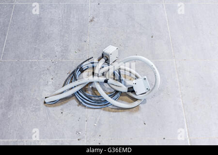 Bunch of various electric cables are coming out from tiled floor. Stock Photo