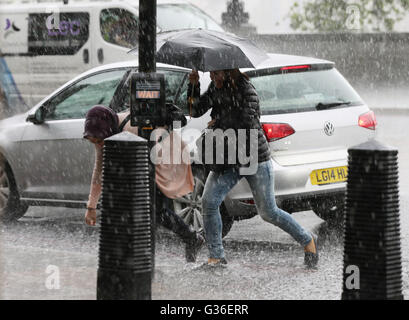 People are caught out in a heavy rain shower in Westminster, London ...