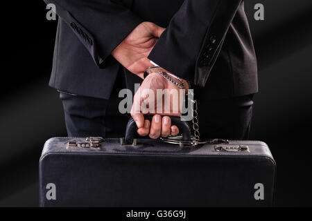 Businessman wearing a suit with a secure suitcase attached with handcuffs Stock Photo