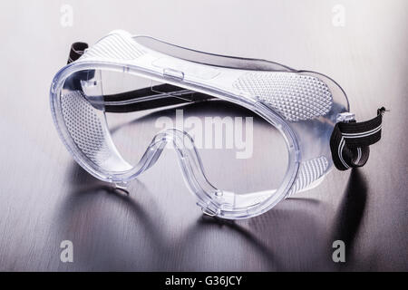 clear safety protective glasses made of plastic on a dark wooden surface Stock Photo