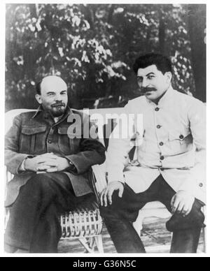 Vladimir Ilyich Lenin (1870 - 1924) and Josef Stalin (1879 - 1953), Communist Russian leaders, sitting on a bench.       Date: circa 1920 Stock Photo