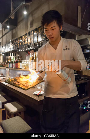Waiter cooks fresh meat with a blow-torch in a restaurant in Kabukicho, Tokyo, Japan Stock Photo