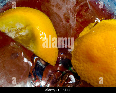 Closeup of Glass containing bubbling clear liquid and lemon slices and ice cubes Stock Photo