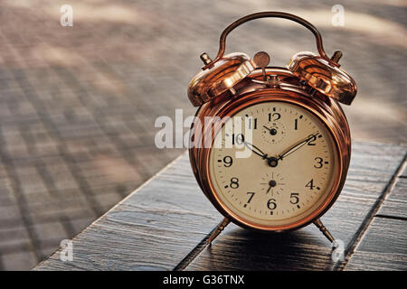 Vintage alarm clock on table and blurry background. Stock Photo