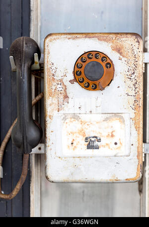 Rusty old vintage rotary pay phone for public use. Old pay telephone with coin slots on a wall. Stock Photo