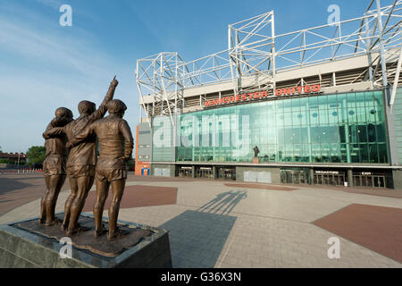 Old Trafford, the stadium of Manchester United Football Club, with the United Trinity statue on a sunny day (Editorial use only)