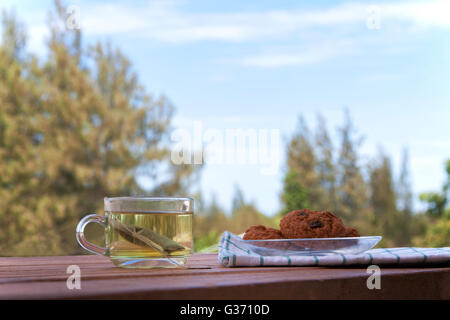 Cup glass of green tea and cookies on wooden background. Light in nature. Stock Photo