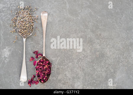Spoonfuls of dried lavender and rose petals on stone surface with copy space Stock Photo